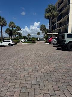 A paved parking lot sits in front of a multi-story building with palm trees nearby — 225 S Beach Road Unit 205, Jupiter FL 33469, JUPITER, FL