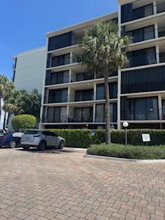 A multi-story apartment building with balconies stands behind a paved parking lot and hedges — 225 S Beach Road Unit 205, Jupiter FL 33469, JUPITER, FL