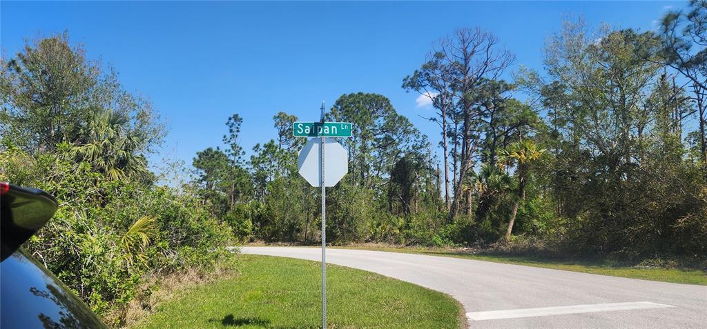 A street sign for Saipan Lane stands next to a stop sign on a paved road — 2157 SAIPAN LANE, PORT CHARLOTTE, FL