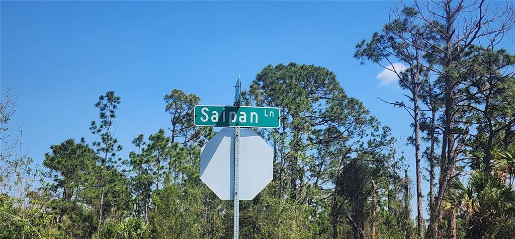 A green street sign labeled Saipan Ln is mounted above a blank white stop sign — 2157 SAIPAN LANE, PORT CHARLOTTE, FL