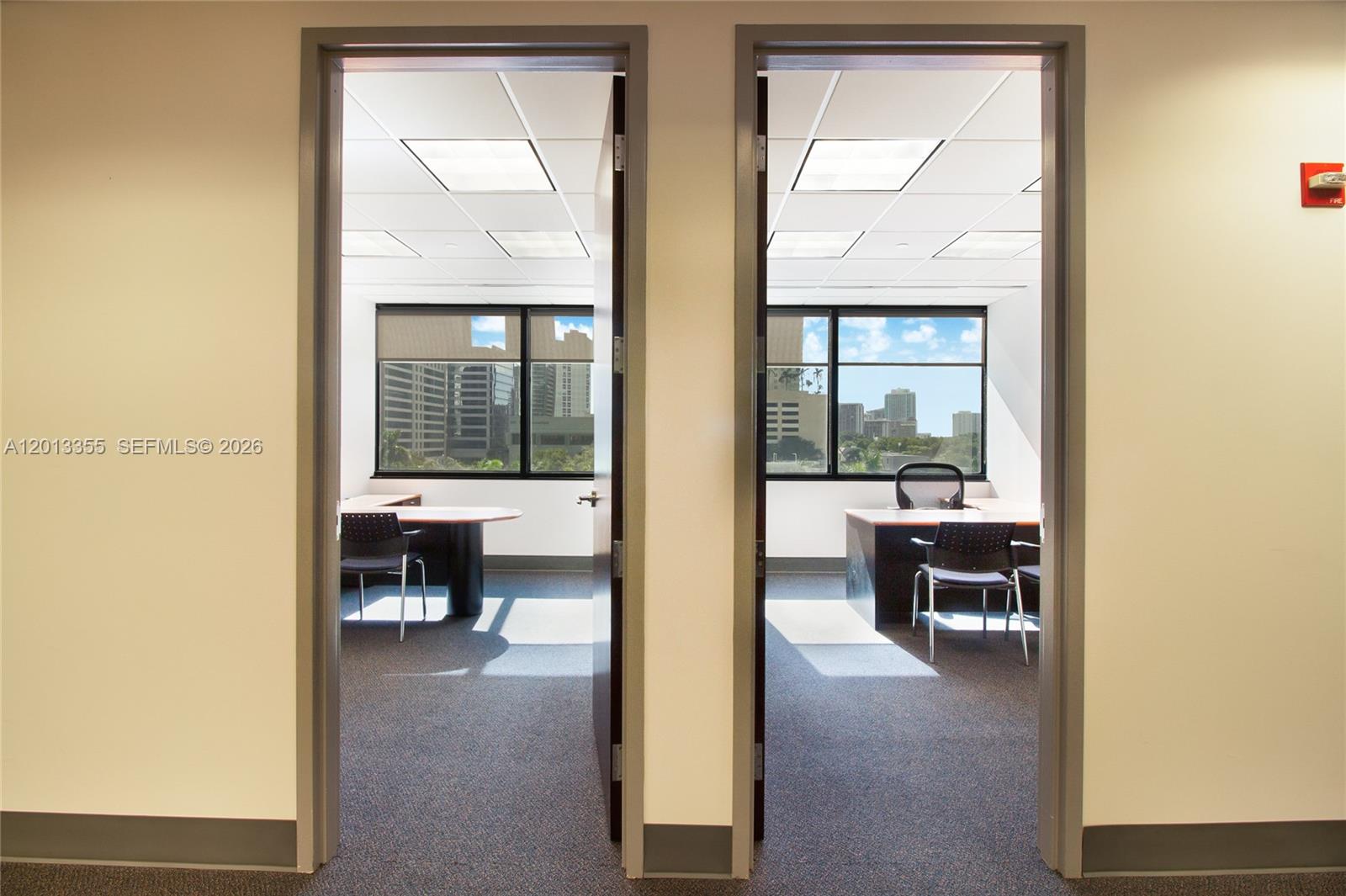 Two adjacent office rooms with desks, chairs, and large windows overlooking a city skyline — 1200 Brickell Ave # B, Miami FL 33131, MIAMI, FL