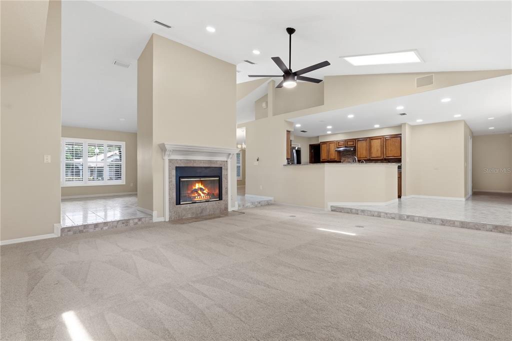 A spacious living room features a fireplace, vaulted ceilings, a ceiling fan, and carpeted flooring — 1889 BERKELEY COURT, MAITLAND, FL