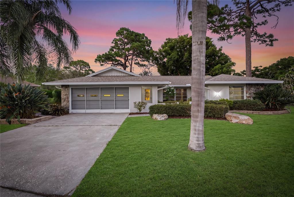 A single-story house with a gray garage door, stone accents, and a palm tree exterior — 505 BAMBOO COURT, TARPON SPRINGS, FL