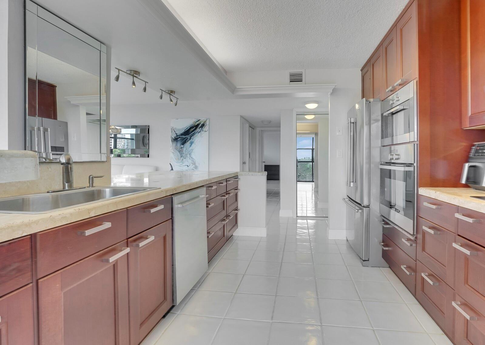A kitchen features wood cabinets, stainless steel appliances, a tile floor, and a stone countertop — 600 Parkview Drive # 531, Hallandale Beach FL 33009, HALLANDALE BEACH, FL