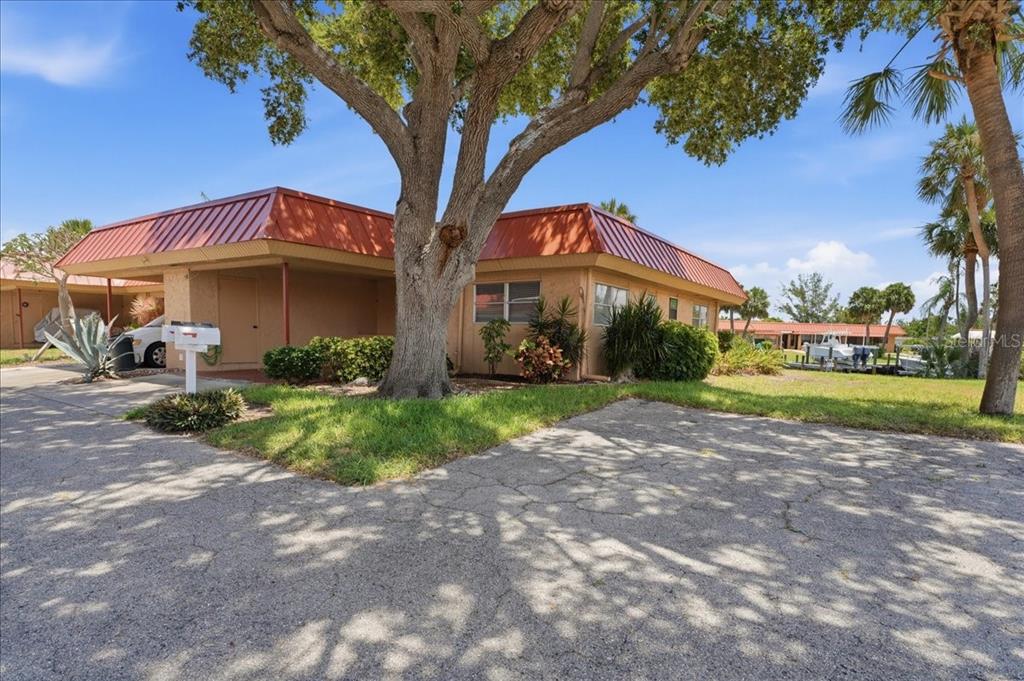 A single-story building with a red metal roof and a large tree in the front — 4111 LA COSTA COVE UNIT 4111, BRADENTON, FL