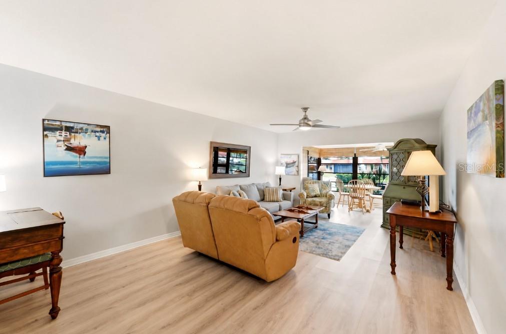 A living room features light wood flooring, a tan sofa, and a dining area beyond — 4111 LA COSTA COVE UNIT 4111, BRADENTON, FL