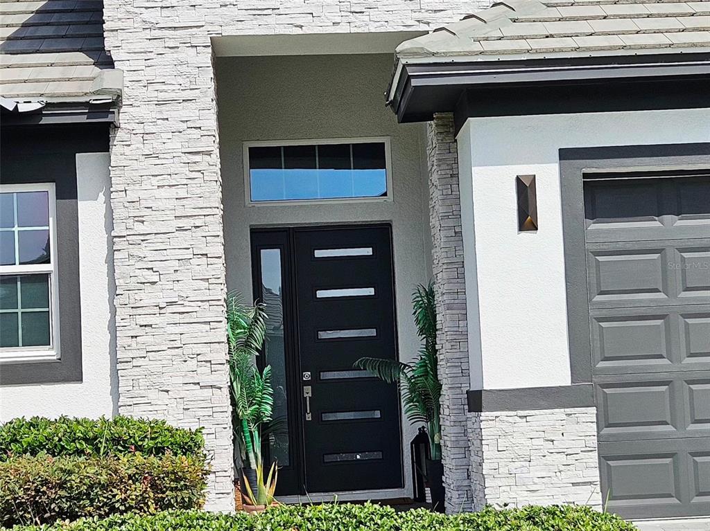 The exterior of a house features a stone facade, a dark front door, and a garage — 260 HAMPTON LOOP, DAVENPORT, FL