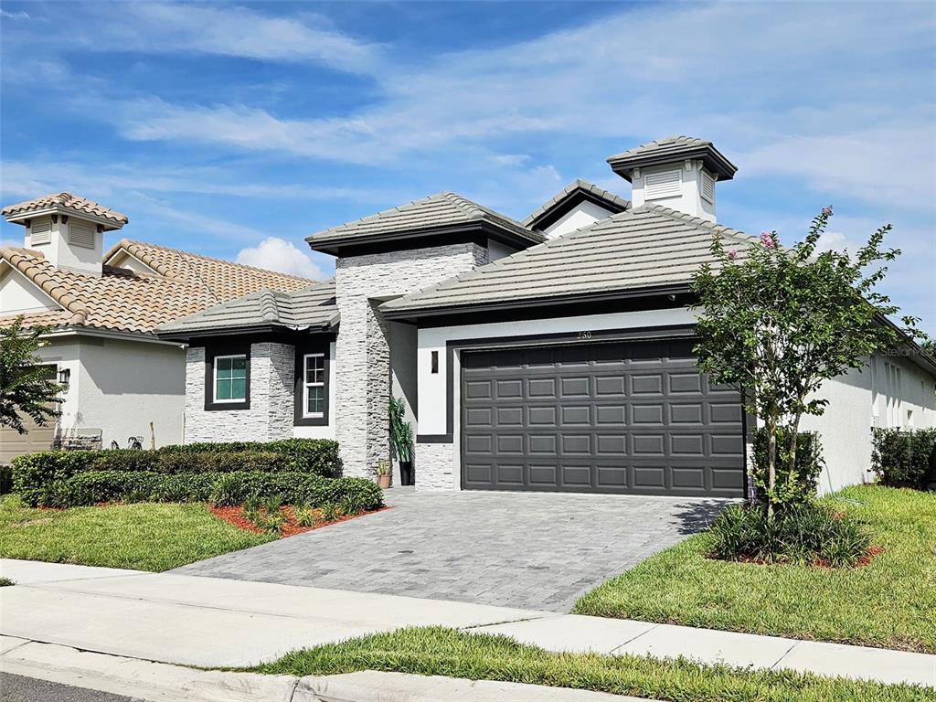 A single-story house with a gray tile roof, stone facade, and a two-car garage — 260 HAMPTON LOOP, DAVENPORT, FL