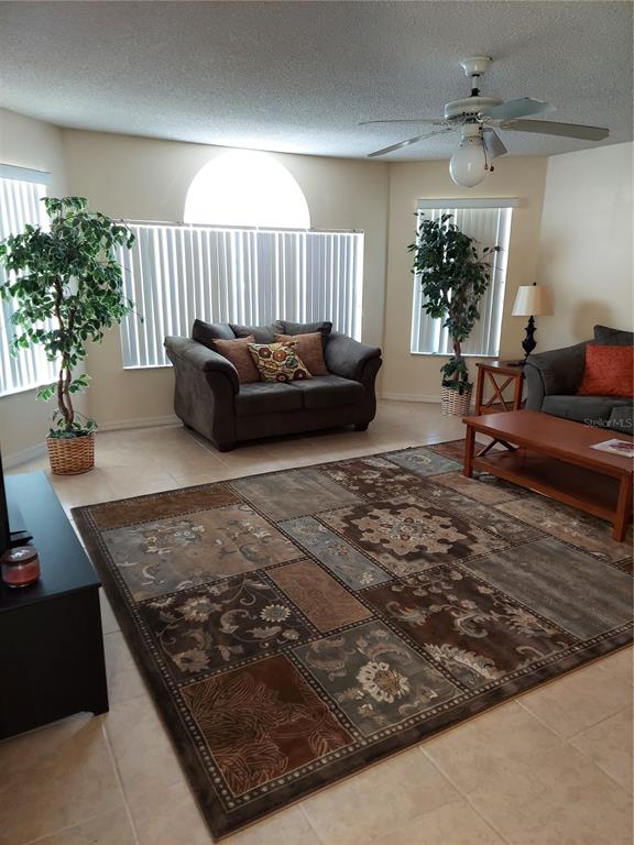 A living room features tile flooring, a large area rug, two sofas, and two potted plants — 2027 ROYAL BAY BOULEVARD UNIT 77, KISSIMMEE, FL
