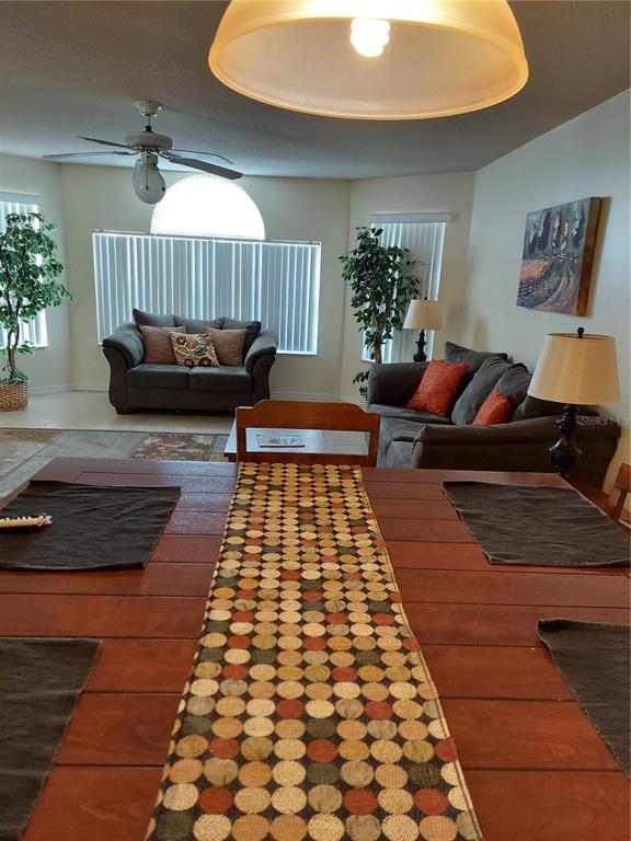 A dining table with a patterned runner sits in the foreground of a living room — 2027 ROYAL BAY BOULEVARD UNIT 77, KISSIMMEE, FL