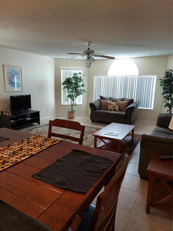 A living and dining area features tile floors, a ceiling fan, and large windows — 2027 ROYAL BAY BOULEVARD UNIT 77, KISSIMMEE, FL