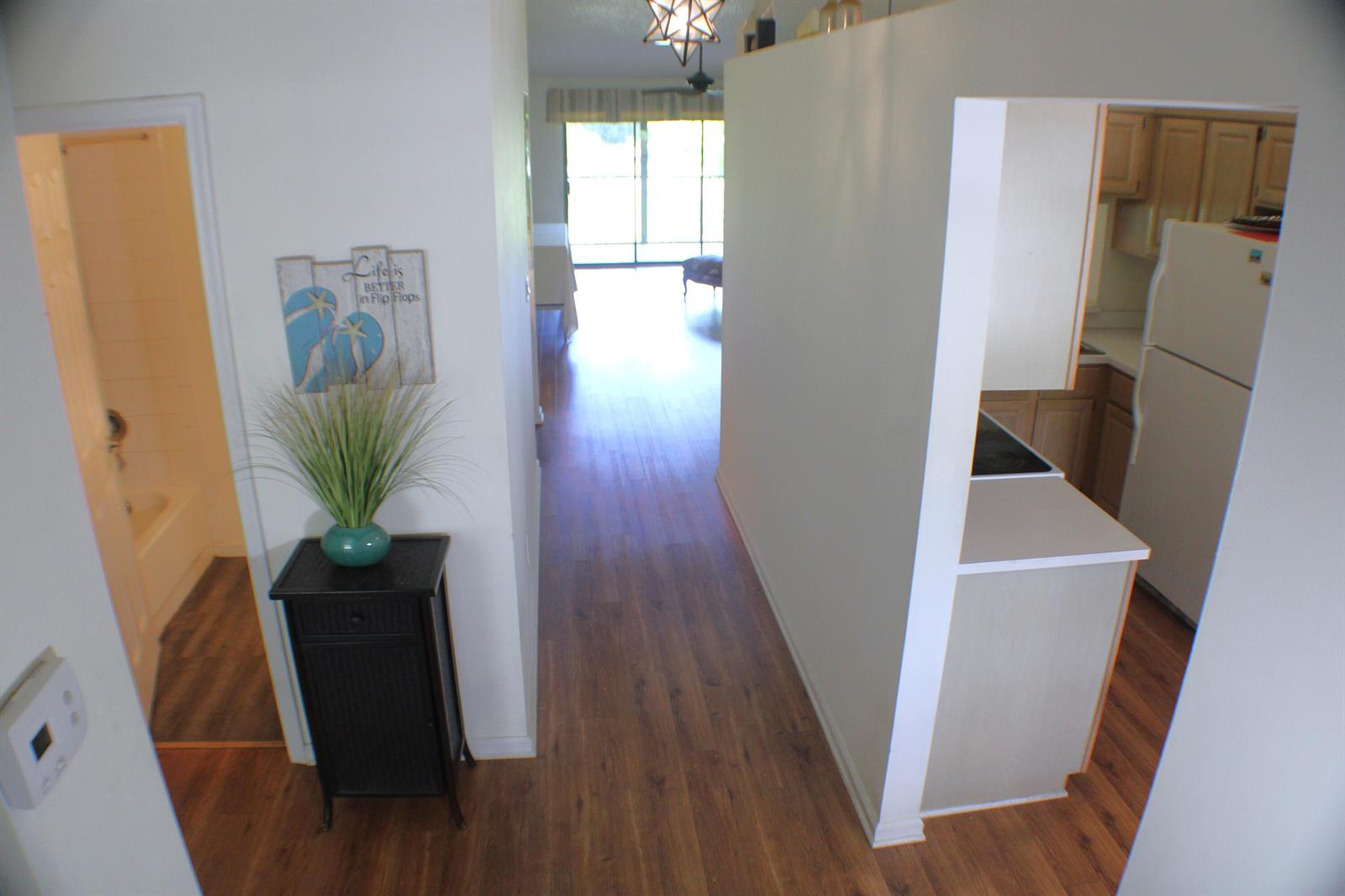 A hallway leads from a bathroom and entryway toward a living area with wood flooring — 1082 Keystone Drive # C, Jupiter FL 33458, JUPITER, FL