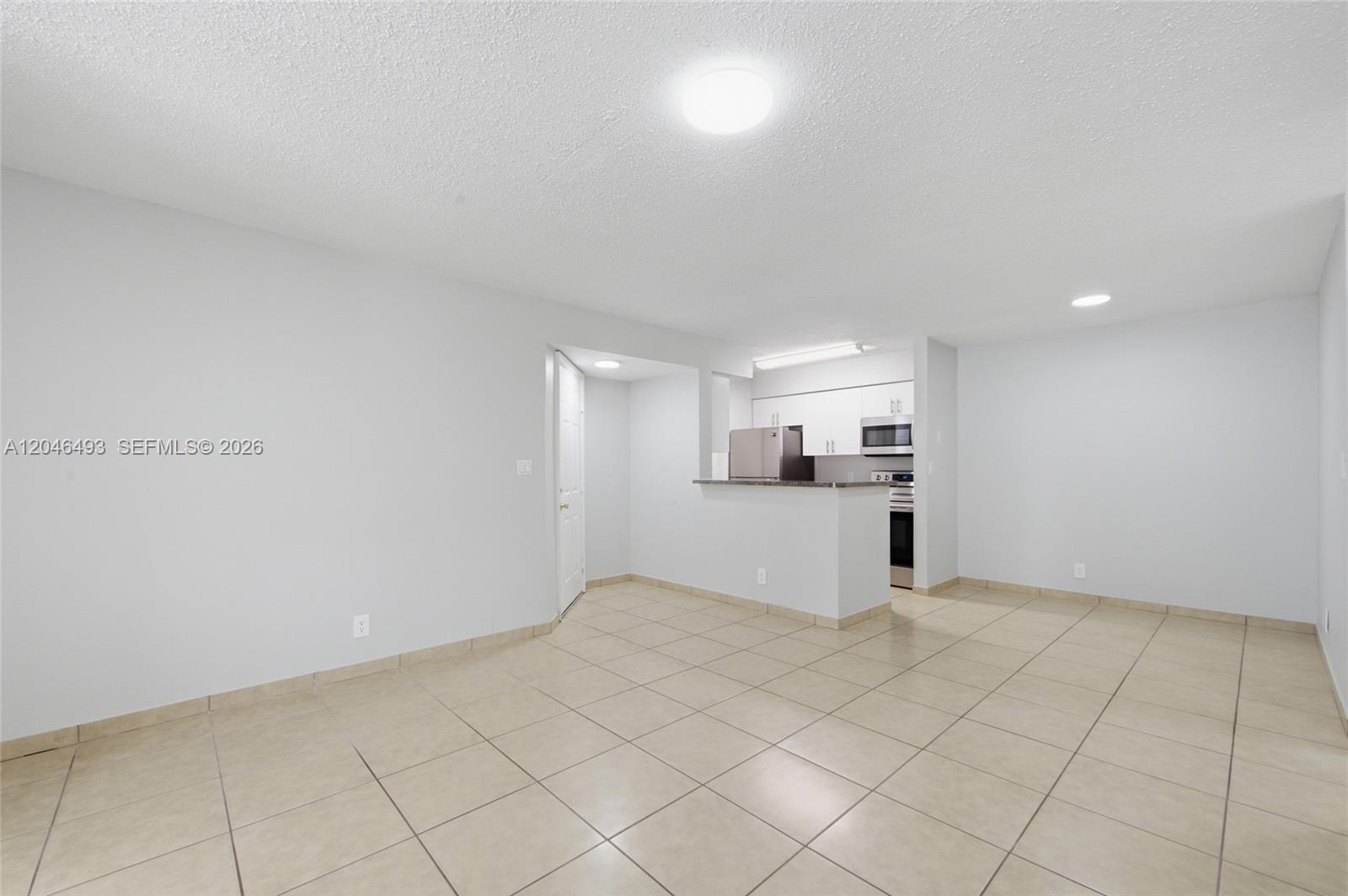 An open-concept living area features light-colored floor tiles and a kitchen with white cabinets — 2846 S University Dr # 4104, Davie FL 33328, DAVIE, FL