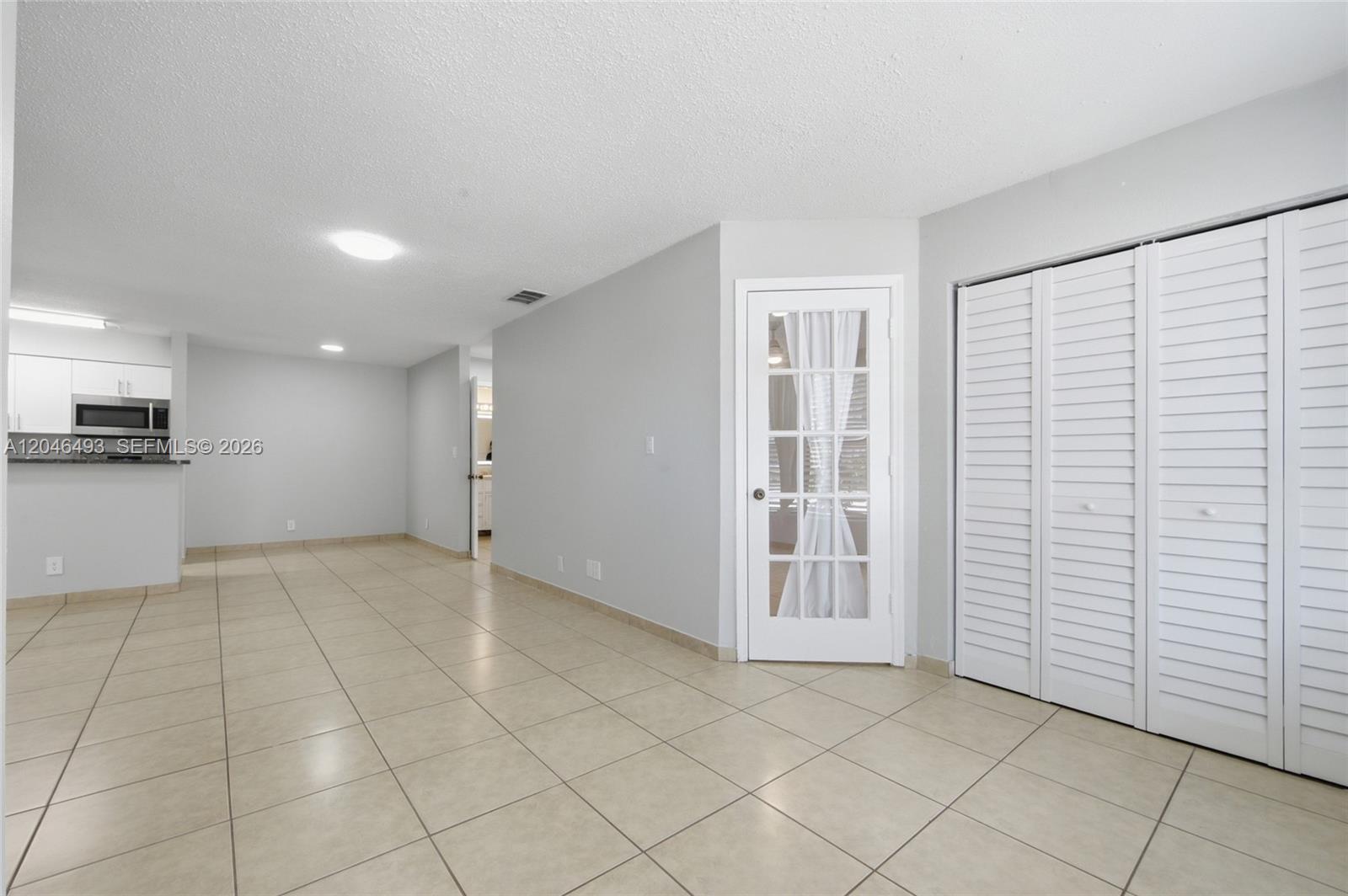 An interior view shows a tiled room with a white French door and louvered closet doors — 2846 S University Dr # 4104, Davie FL 33328, DAVIE, FL