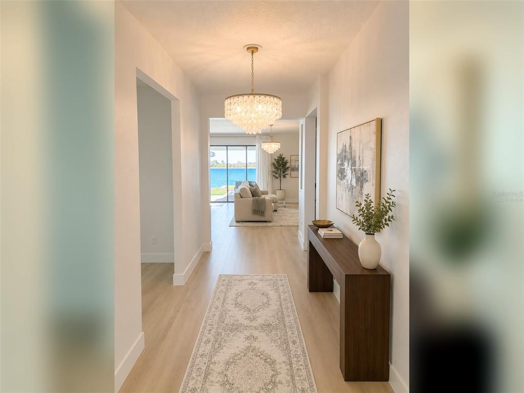 A bright hallway with light wood floors leads to a living area overlooking a lake — 14048 LARKSPUR LAKE DRIVE, WINTER GARDEN, FL