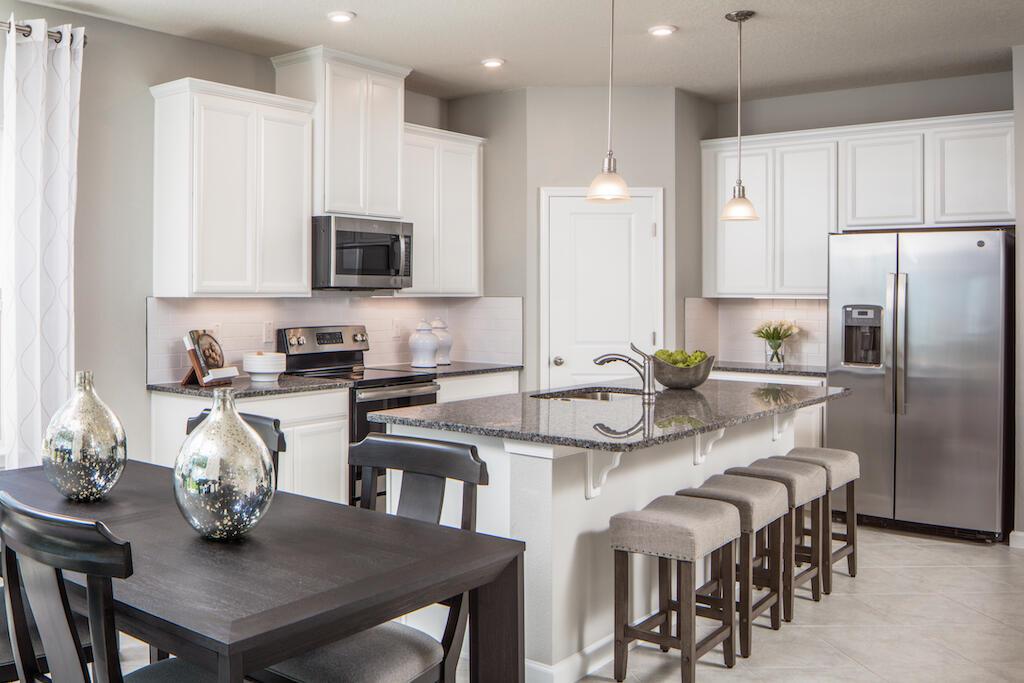 A kitchen with white cabinets, granite countertops, a center island, and a dining table — SEBASTIAN, FL