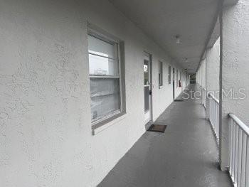 An exterior walkway with white stucco walls and a metal railing overlooks a building corridor — 3124 LAKE BAYSHORE DRIVE UNIT 219, BRADENTON, FL
