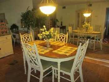 A dining room features a round wooden table with white lattice-back chairs and pendant lighting — 3124 LAKE BAYSHORE DRIVE UNIT 219, BRADENTON, FL