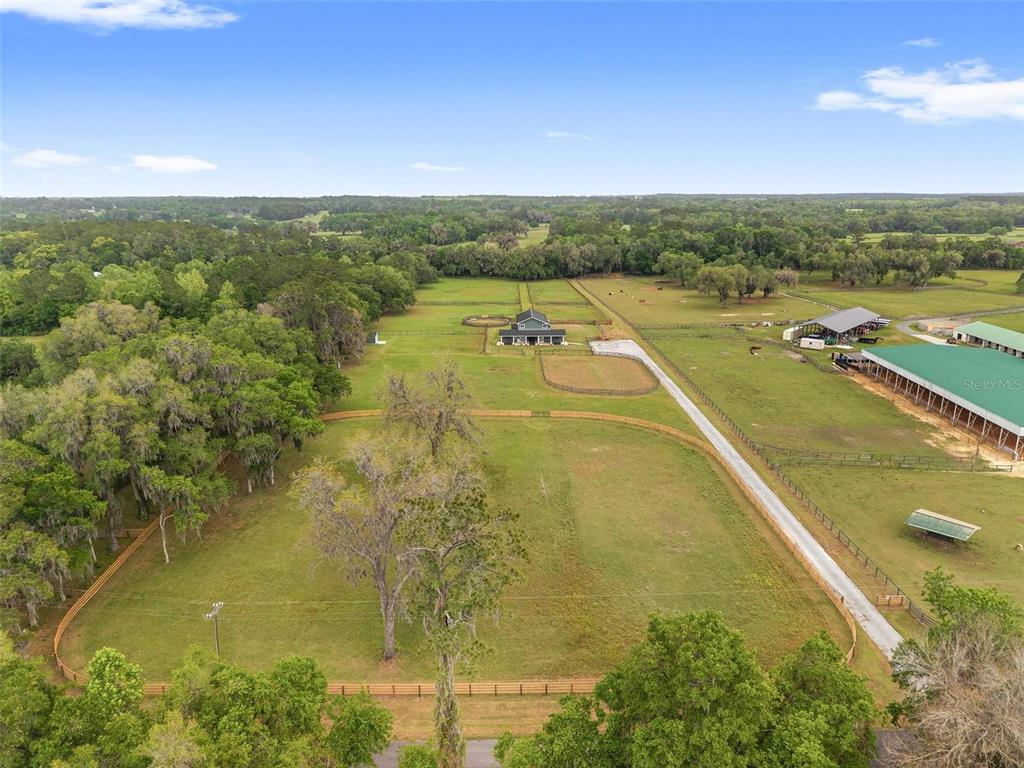 An aerial view shows a rural property with fenced pastures, a house, and large barns — 16201 NW 162ND TERRACE, WILLISTON, FL