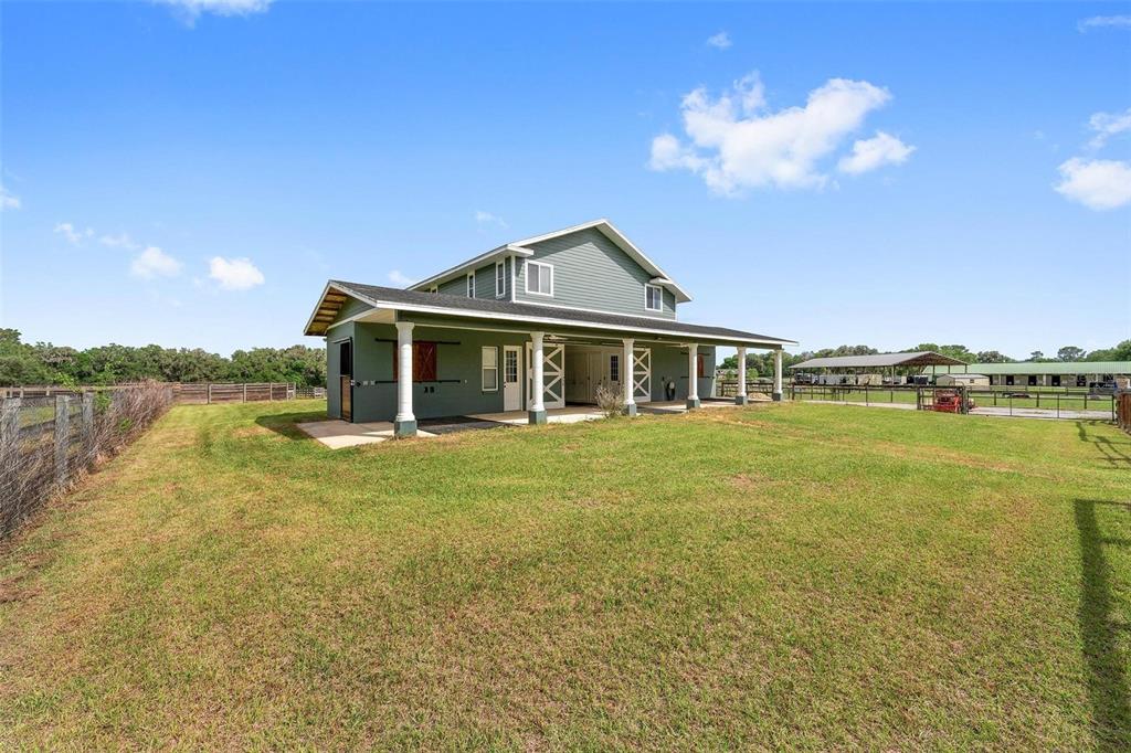 A two-story house with a wrap-around porch and horse stalls stands on a grassy lot — 16201 NW 162ND TERRACE, WILLISTON, FL