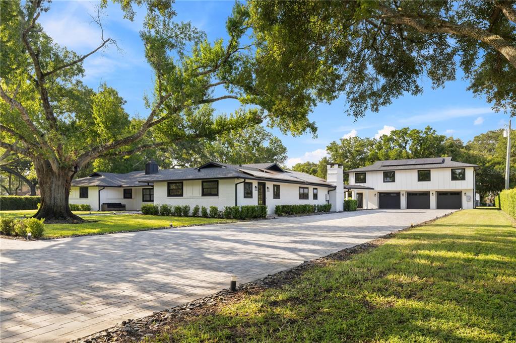 A paved driveway leads through a gated entrance to a white house with a garage — 900 W PLANT STREET, WINTER GARDEN, FL
