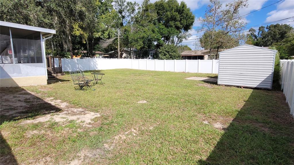 A fenced backyard features a grass lawn, a metal storage shed, and a patio area — 9 NEW YORK BOULEVARD, BEVERLY HILLS, FL