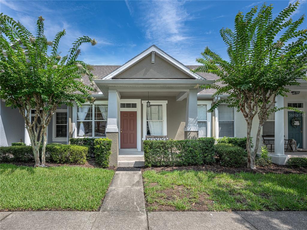 A tan house with a red front door, a covered porch, and two small trees — 14655 WATER LOCUST DRIVE, ORLANDO, FL