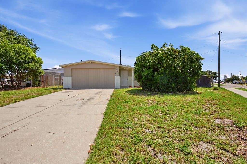 A single-story house with a beige exterior, a garage, and a large bush in front — 4506 POOLE STREET, NEW PORT RICHEY, FL