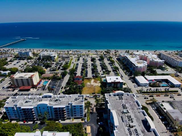Aerial view of a coastal town featuring multi-story buildings, a large parking lot, and beach — 120 S Ocean Drive, Deerfield Beach FL 33441, DEERFIELD BEACH, FL