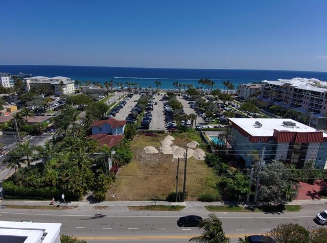 An aerial view shows a vacant lot situated between buildings near a beach and parking lot — 120 S Ocean Drive, Deerfield Beach FL 33441, DEERFIELD BEACH, FL