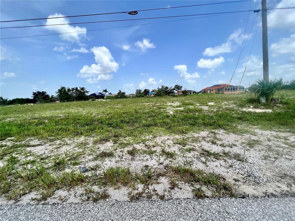 A vacant, grassy lot with sandy patches under a blue sky with scattered clouds — 3061 NW 5TH AVENUE, CAPE CORAL, FL