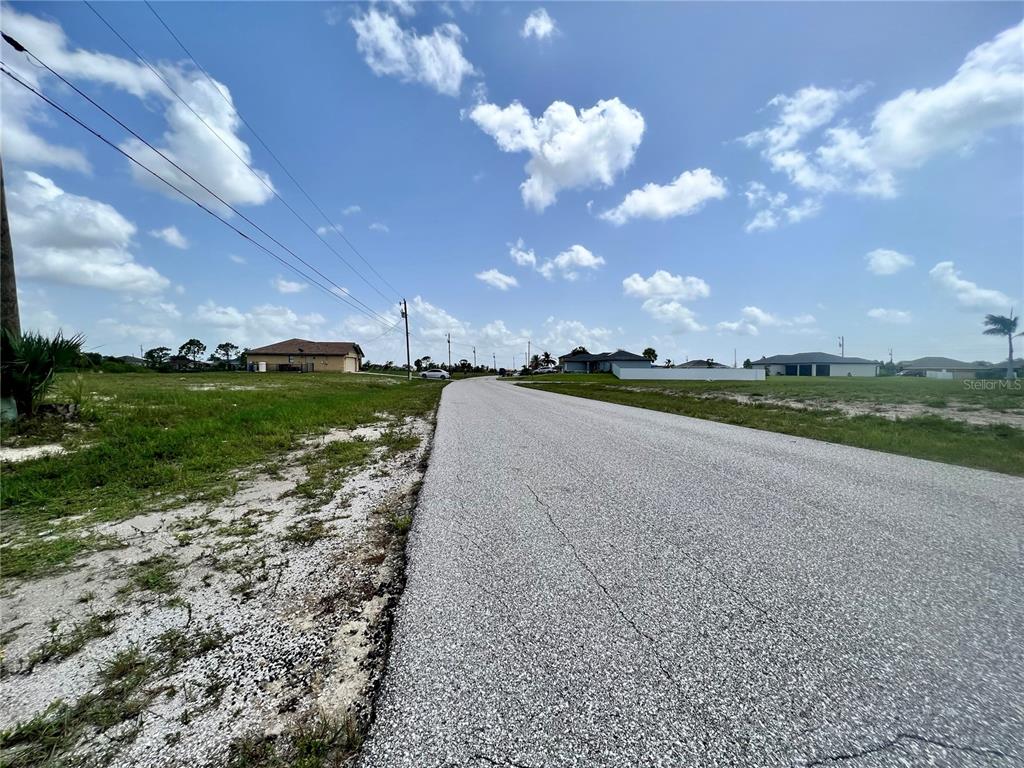 A paved road runs through a residential area with vacant lots and scattered houses — 3061 NW 5TH AVENUE, CAPE CORAL, FL