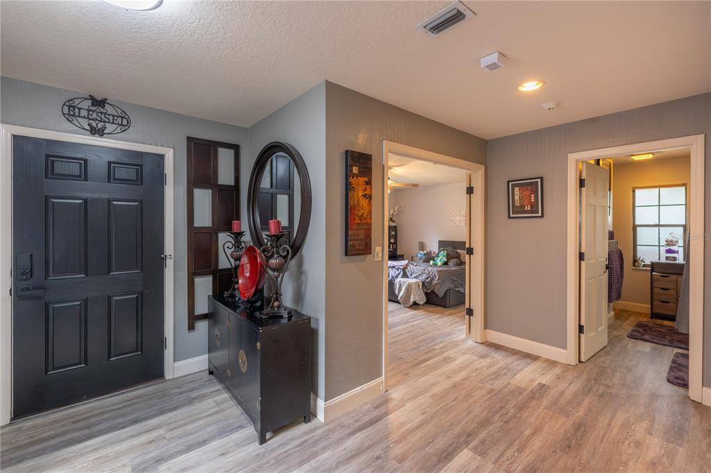 An entryway features a dark front door, wood-look flooring, and a black console table — 2550 SE 40TH STREET, OCALA, FL