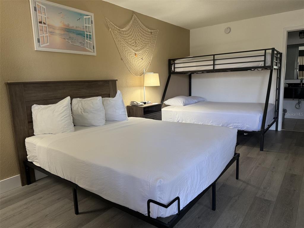 A bedroom features a queen bed, a metal bunk bed, and light wood-look flooring — 7150 N TAMIAMI TRAIL UNIT S510, SARASOTA, FL