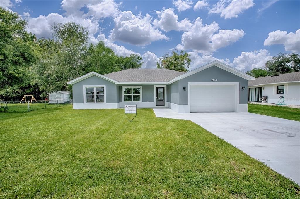 A single-story house with a gray exterior, white trim, and a two-car garage — 557 COUNTY ROAD 487, LAKE PANASOFFKEE, FL