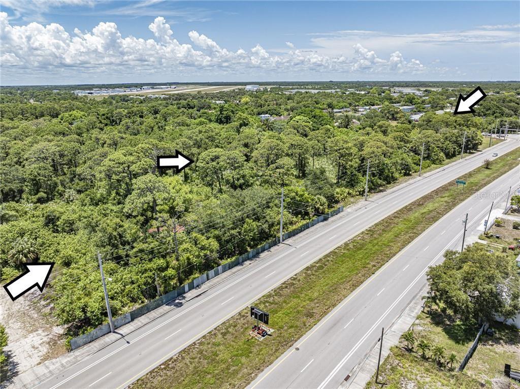 An aerial view shows a heavily wooded lot bordering a multi-lane highway — 2551 ST LUCIE BOULEVARD, FORT PIERCE, FL