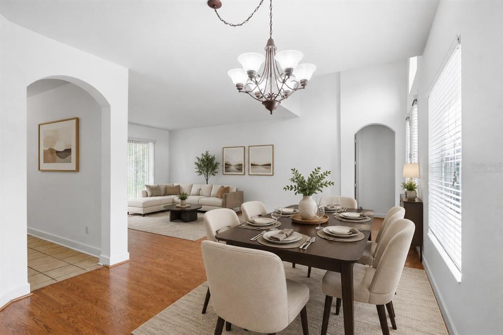 A dining area with a chandelier and table opens into a living room with hardwood floors — 3476 FOREST RIDGE LANE, KISSIMMEE, FL