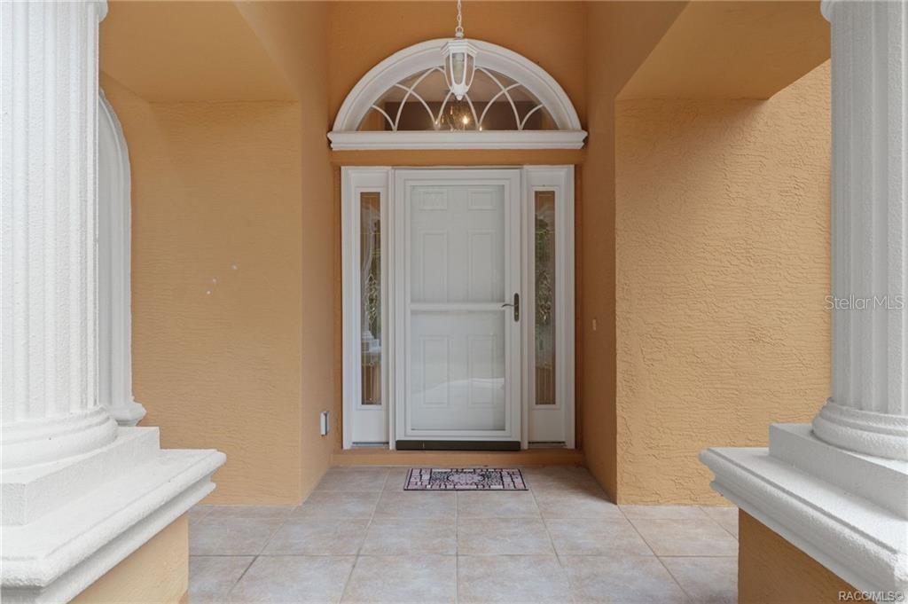 A white front door with sidelights and a fanlight window sits under a covered porch — 7145 SW 181ST AVENUE, DUNNELLON, FL