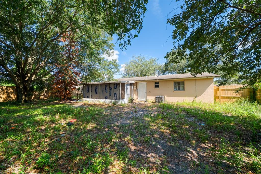 The backyard of a house features a screened-in porch with Lowe's branded protective sheeting — 2913 KEESLER STREET, DELTONA, FL