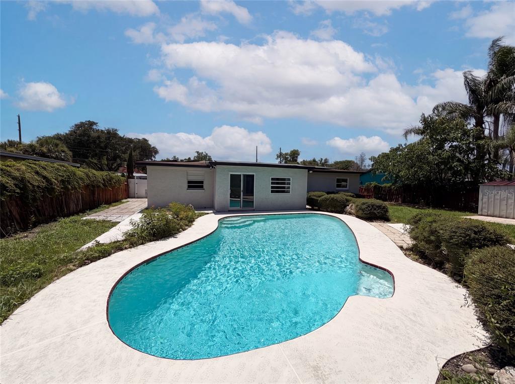 A backyard features a kidney-shaped swimming pool with a white concrete deck and a house — 1907 SUE ANN STREET, ORLANDO, FL