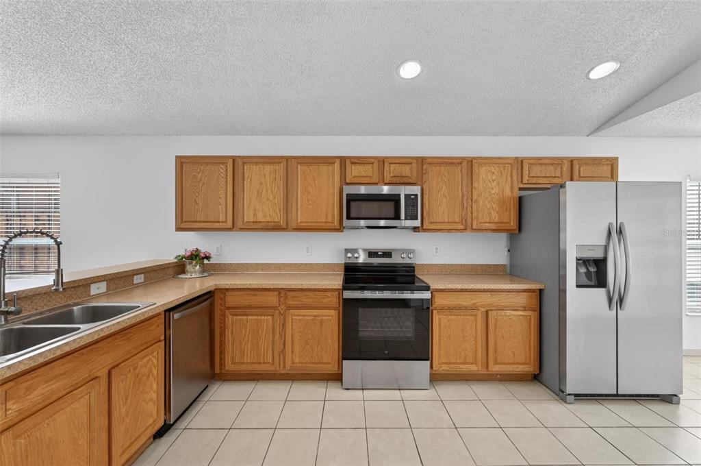 A kitchen featuring oak cabinets, stainless steel appliances, and light-colored tile flooring — 2041 NEWTOWN ROAD, GROVELAND, FL