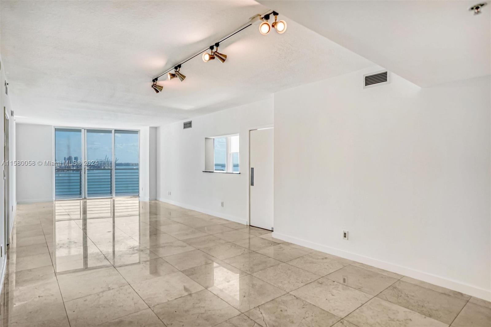 An empty room with light-colored tile floors, a track lighting fixture, and a balcony view — 325 NE Biscayne Blvd # 1923, Miami FL 33131, MIAMI, FL
