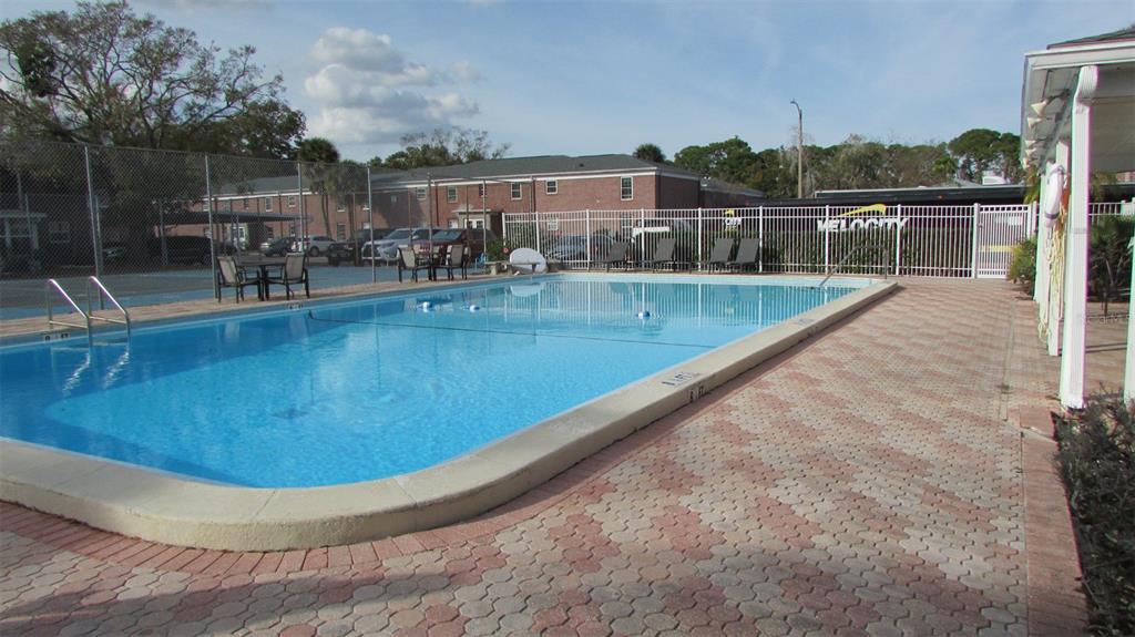 An outdoor swimming pool with a brick paver deck and a white metal fence — 8500 13TH STREET N UNIT A, ST PETERSBURG, FL
