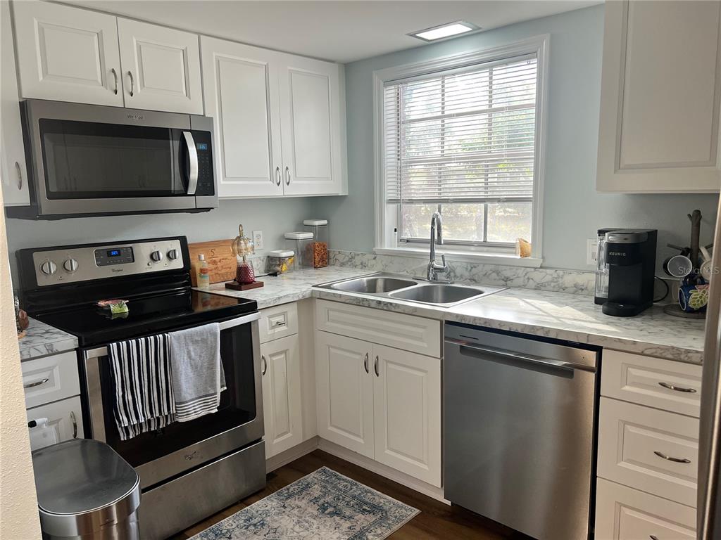 A kitchen features white cabinets, stainless steel appliances, and a marble-patterned countertop — 8500 13TH STREET N UNIT A, ST PETERSBURG, FL