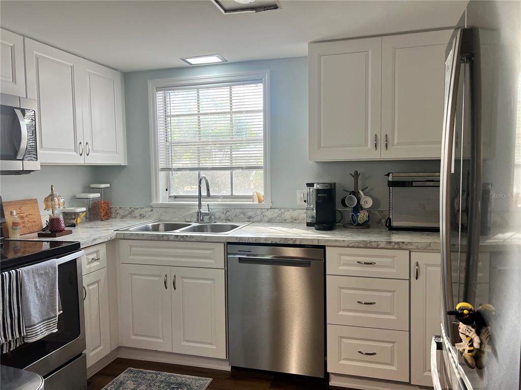 A kitchen features white cabinets, stainless steel appliances, and marble-patterned countertops — 8500 13TH STREET N UNIT A, ST PETERSBURG, FL