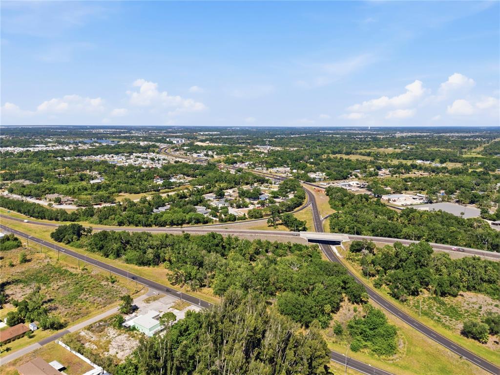 An aerial view shows a highway overpass surrounded by trees and residential neighborhoods — 4340 US 19, PALMETTO, FL