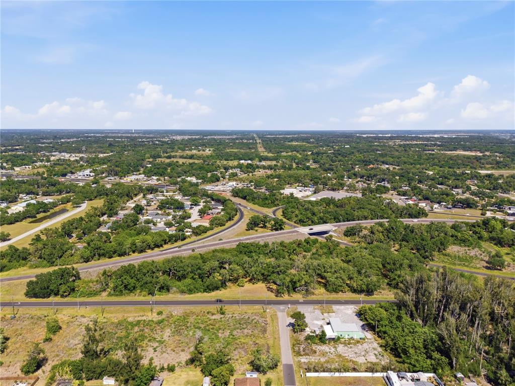 An aerial view shows a highway interchange surrounded by trees, fields, and scattered residential buildings — 4340 US 19, PALMETTO, FL