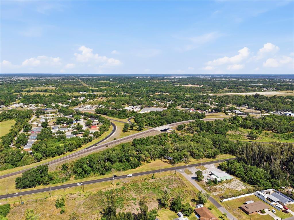 An aerial view shows a highway overpass, surrounding wooded areas, and scattered residential buildings — 4340 US 19, PALMETTO, FL