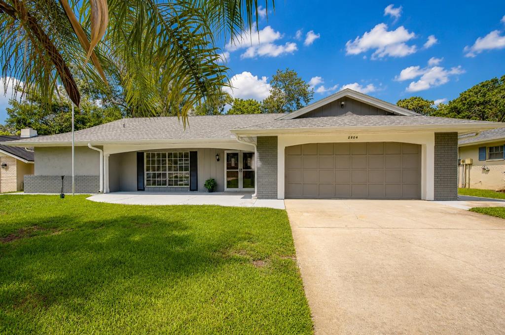 A single-story house with a gray brick facade, a two-car garage, and a front lawn — 8804 VILLAGE MILL ROW, HUDSON, FL
