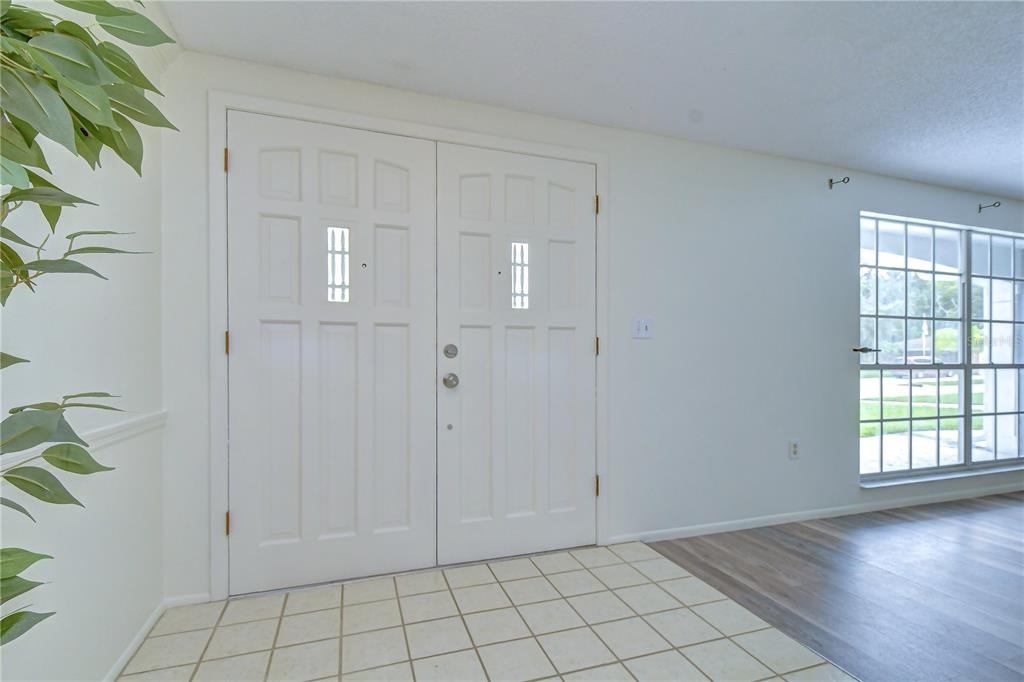 A white double front door opens into a foyer with tiled flooring and a window — 8804 VILLAGE MILL ROW, HUDSON, FL